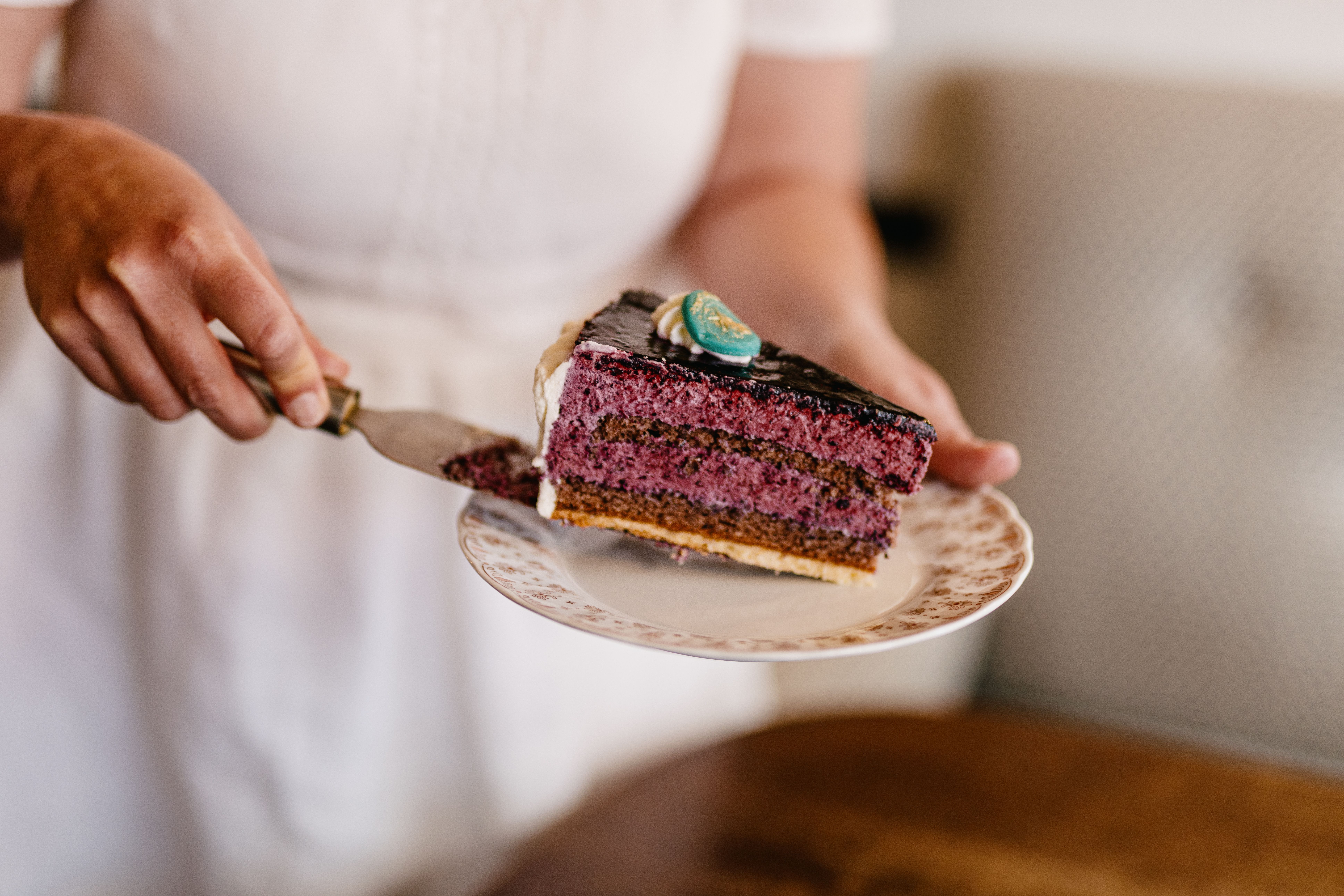 Eine Person legt ein Stück Kuchen auf einen Teller. 