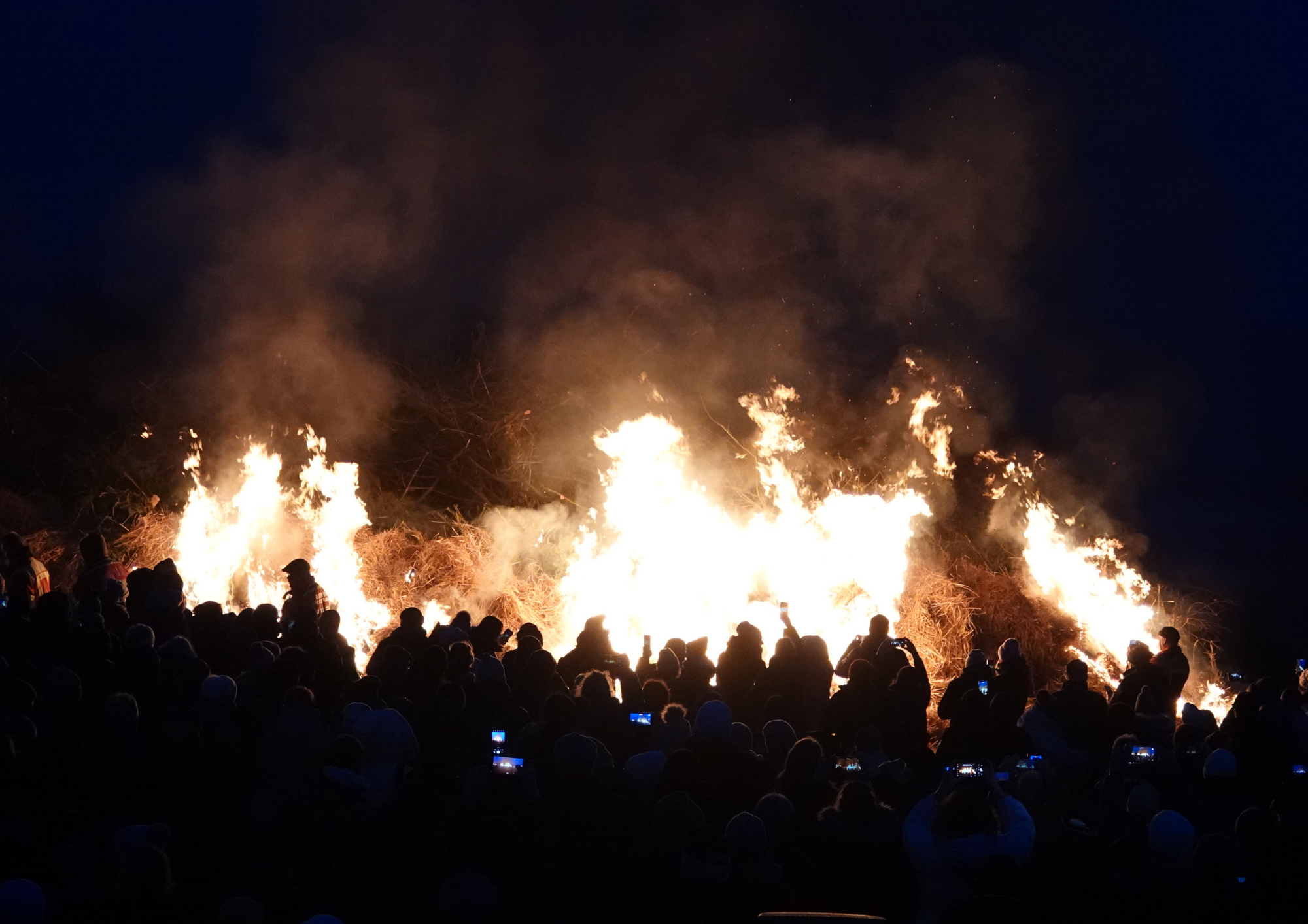 Menschen stehen um das große Biike-Feuer.