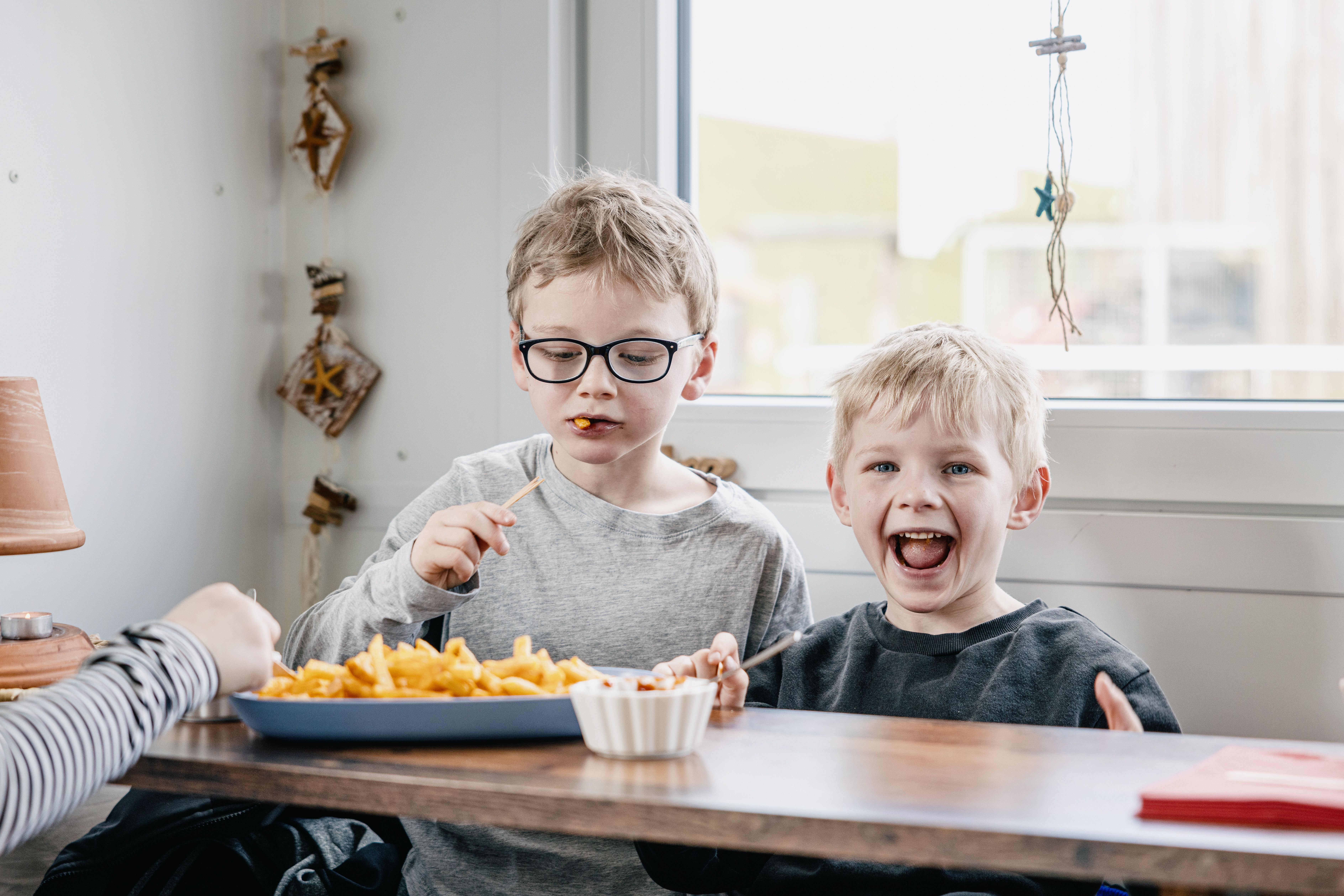 Zwei Jungs essen Pommes in einem Bistro. Verlinkung auf Unterseite "Familienfreundliche Unterkünfte".