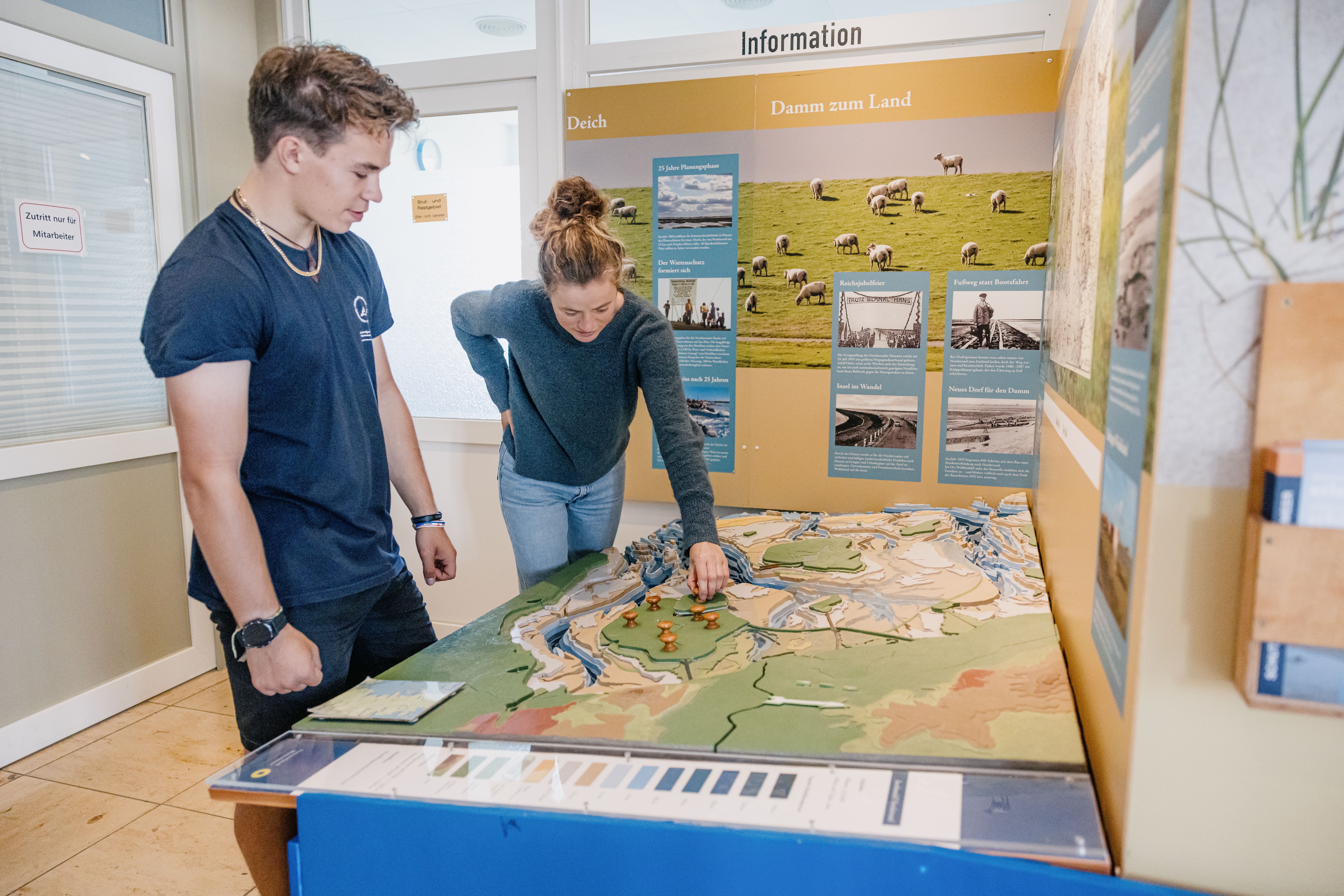 Ein Freiwilliger der Schutzstation zeigt einer Dame die Ausstellung im Nationalparkhaus Nordstrand. 