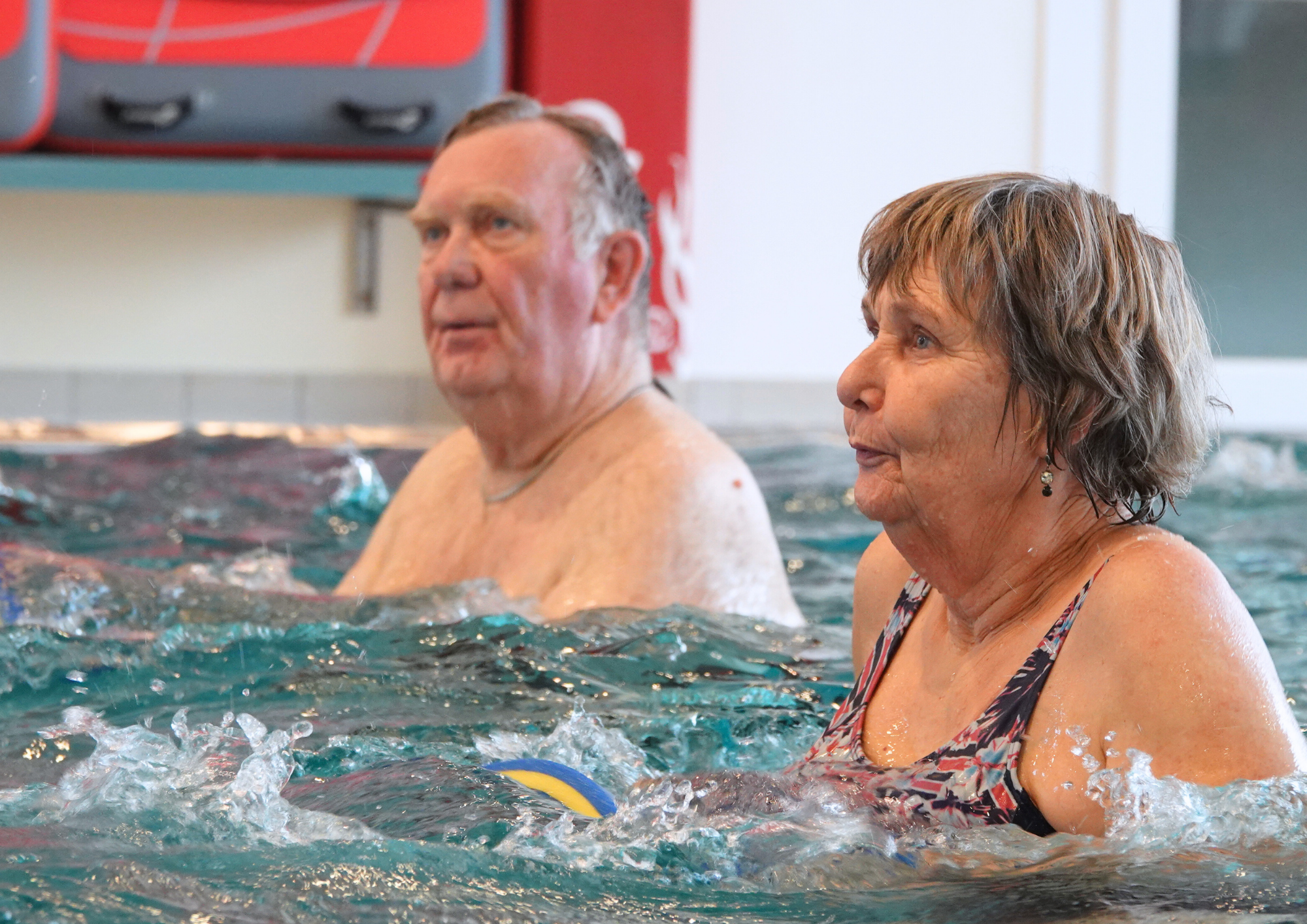 Zwei ältere Personen stehen beim Aquafitness im Schwimmbecken. 