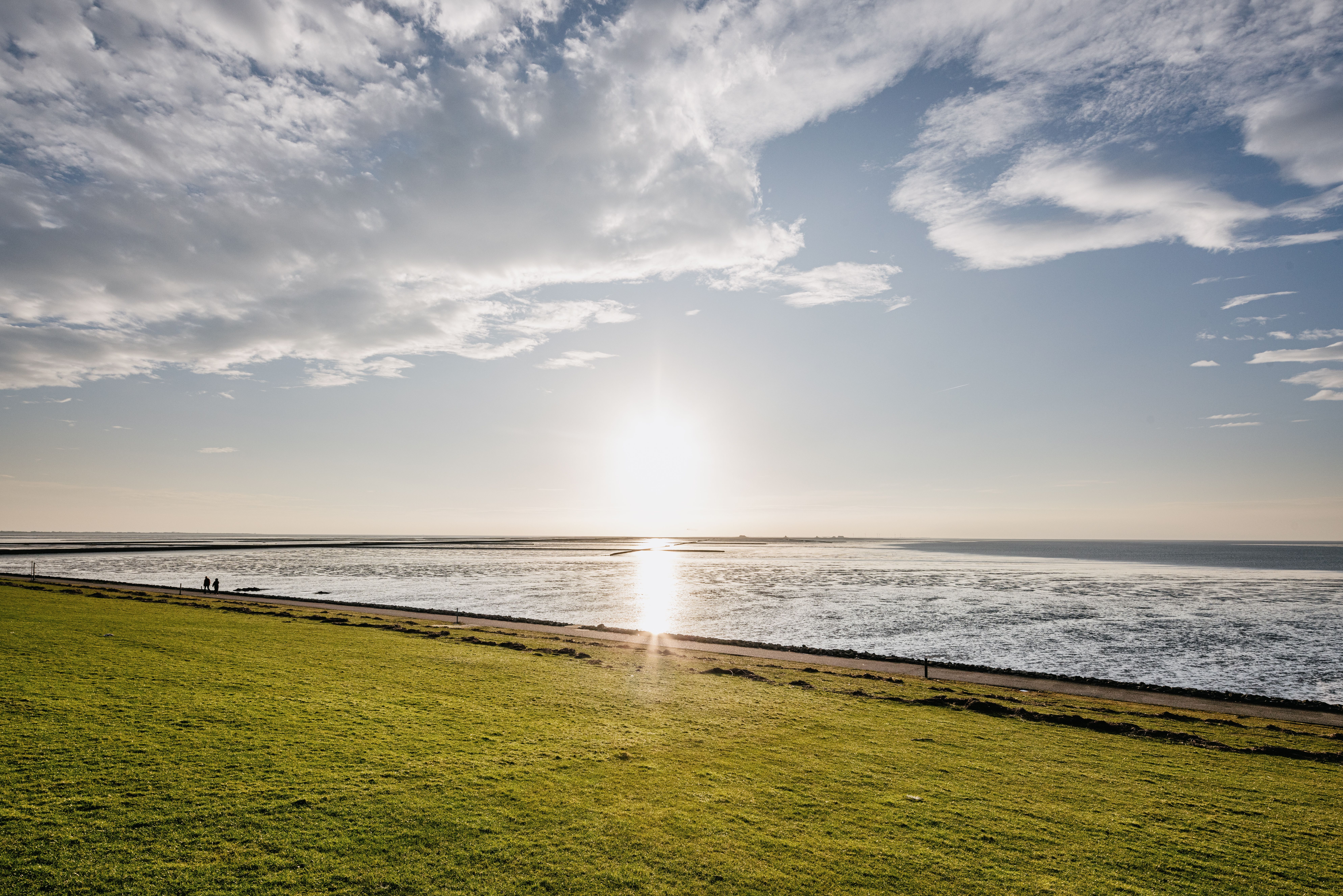 Blick vom Deich auf den Sonnenuntergang über dem Wattenmeer. 