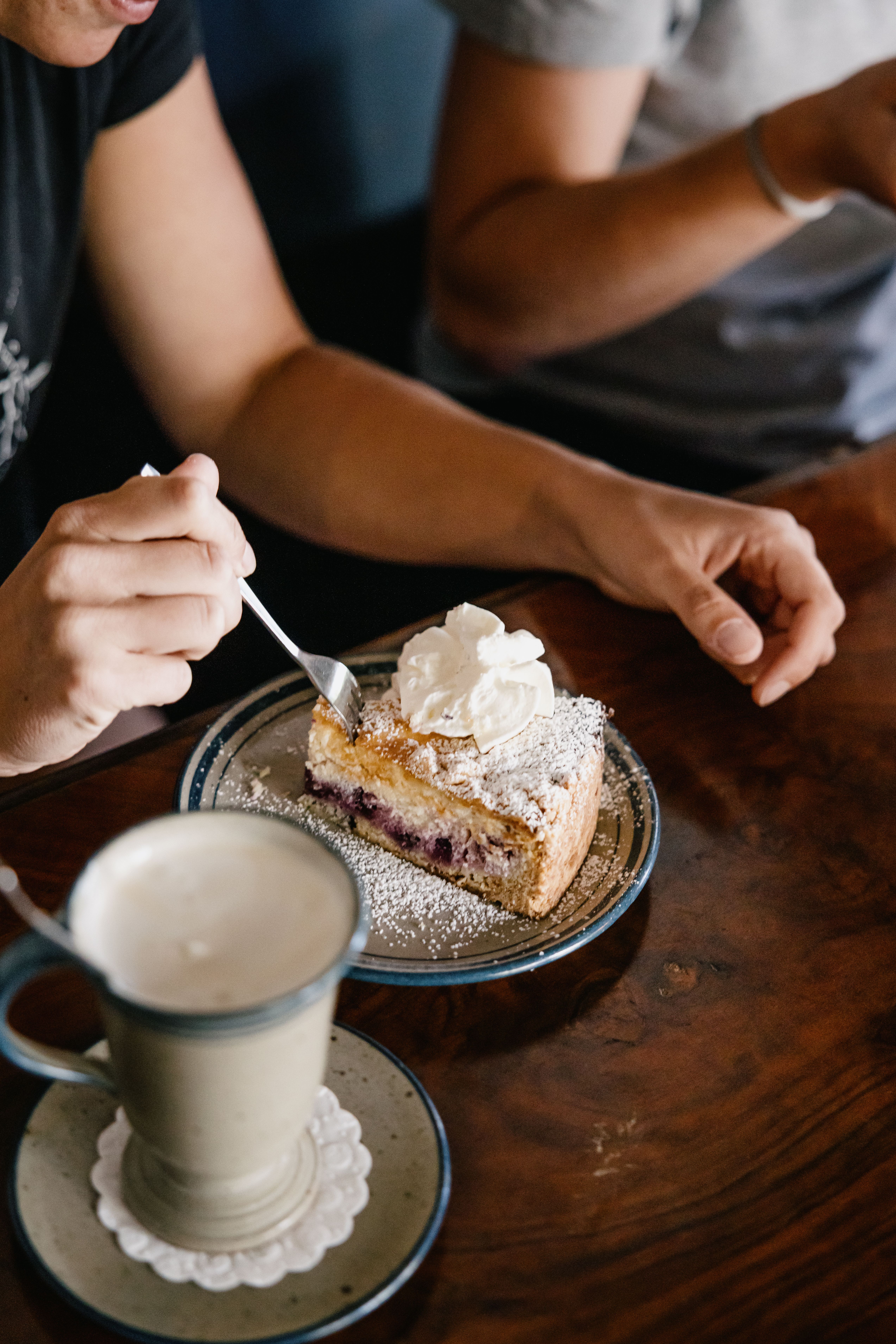 Eine Person nimmt sich ein Stück Torte mit Sahne. 