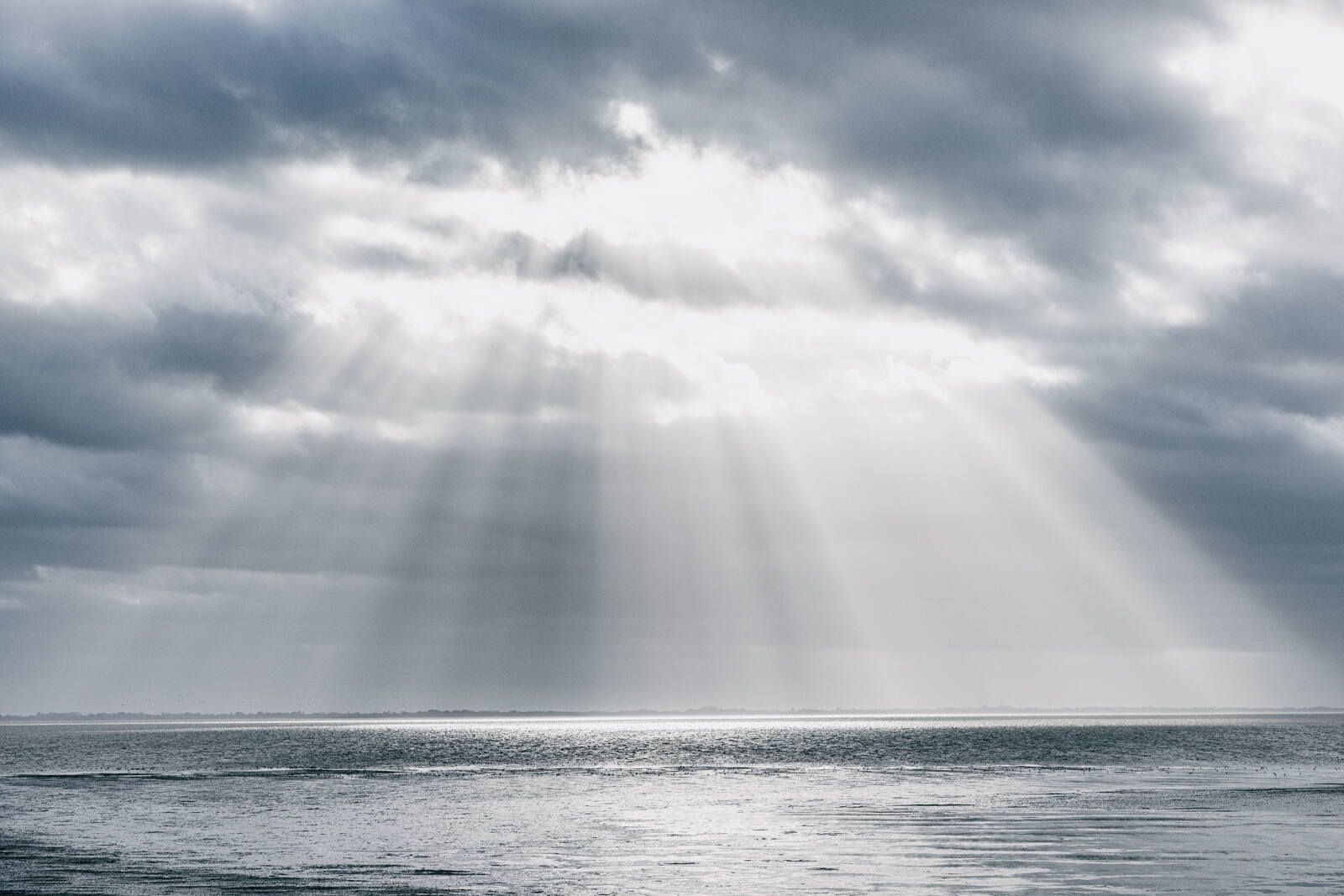 Sonnenstrahlen durch Wolken über der Nordsee. Verlinkung auf Unterseite "Wetter & Gezeiten".