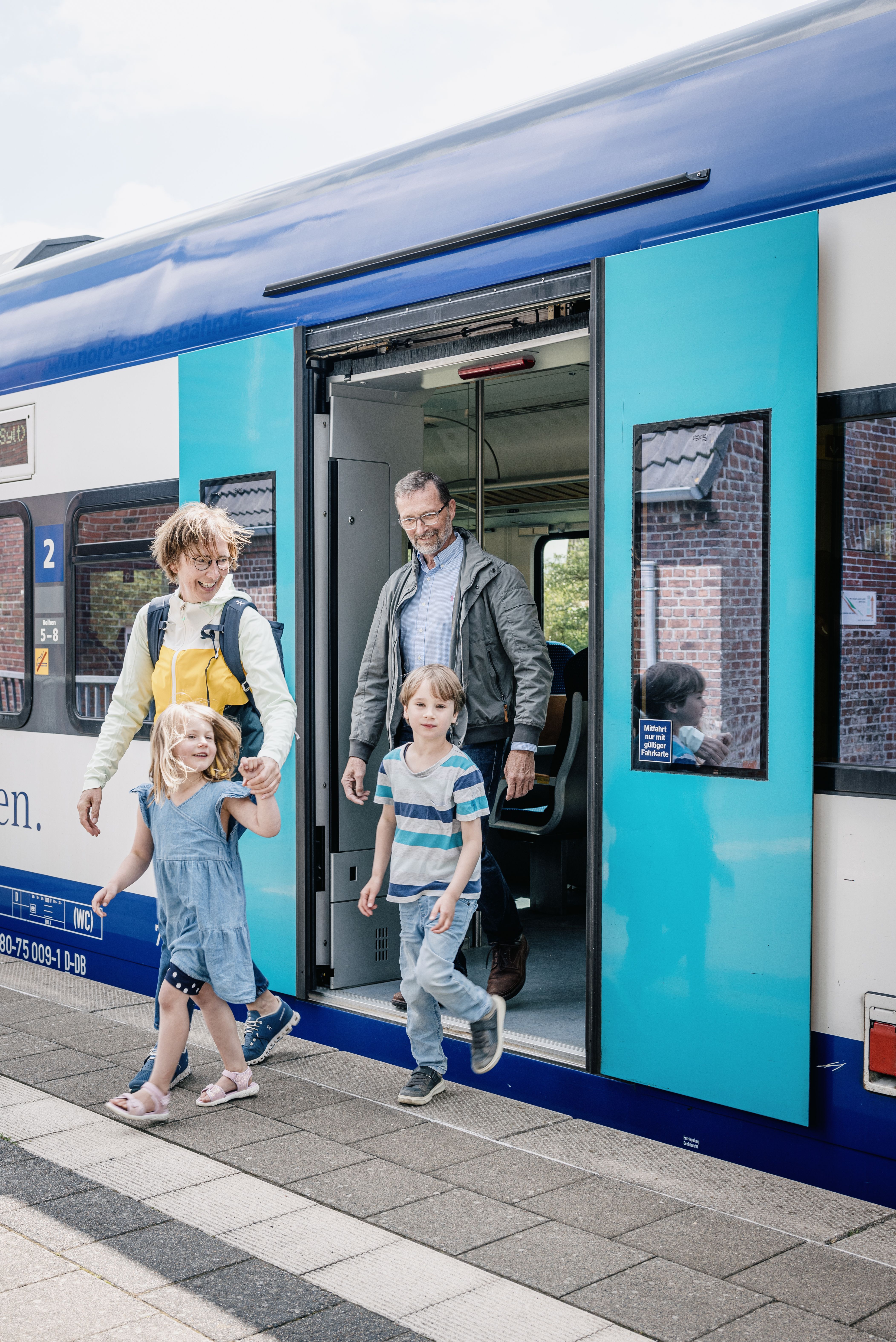 Eine Familie mit zwei Kindern steigt aus dem Zug aus. 