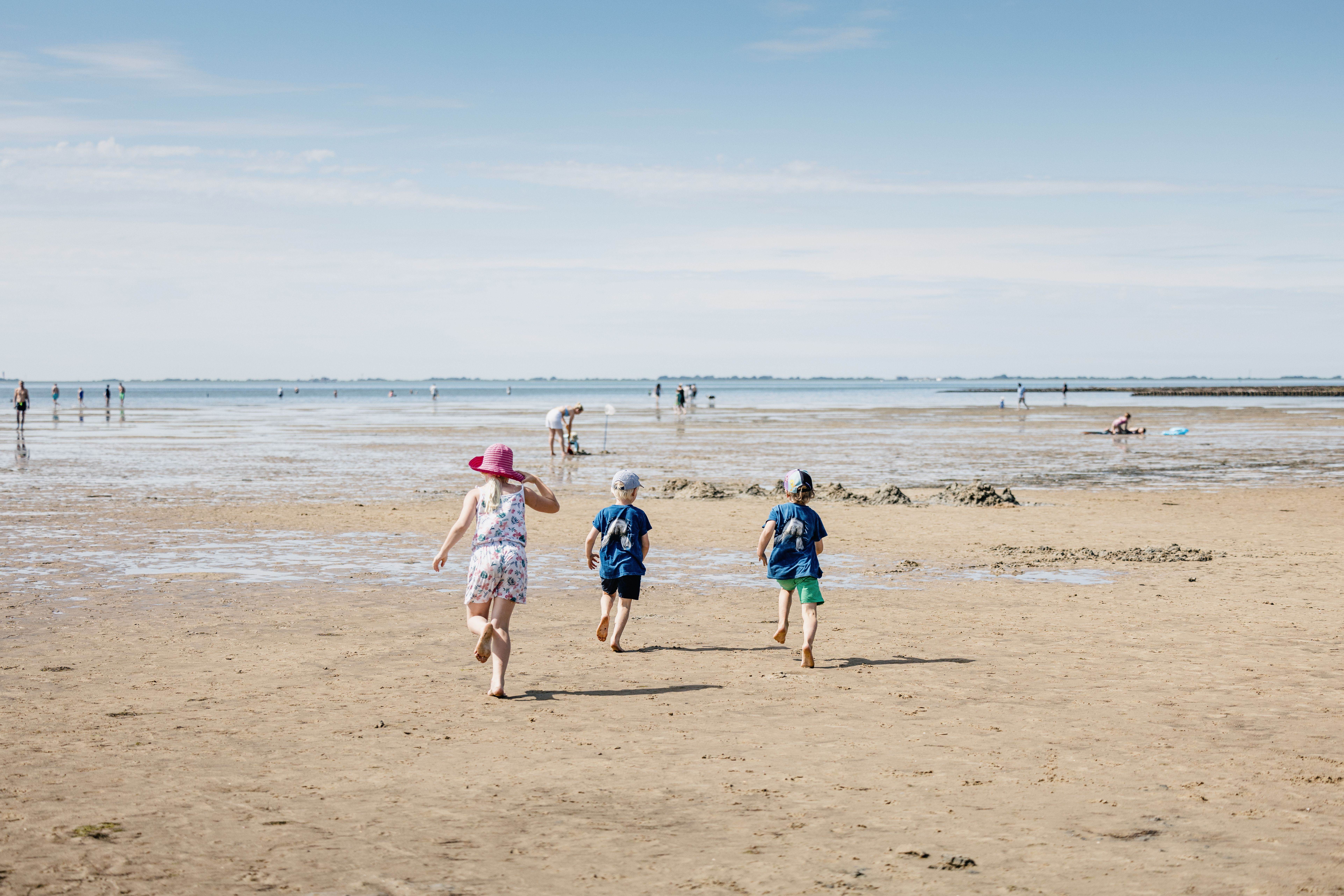 Zwei kleine Jungs und ein kleines Mädchen laufen übers Watt Richtung Meer. Verlinkung zur Unterseite "Bade- und Strandurlaub".