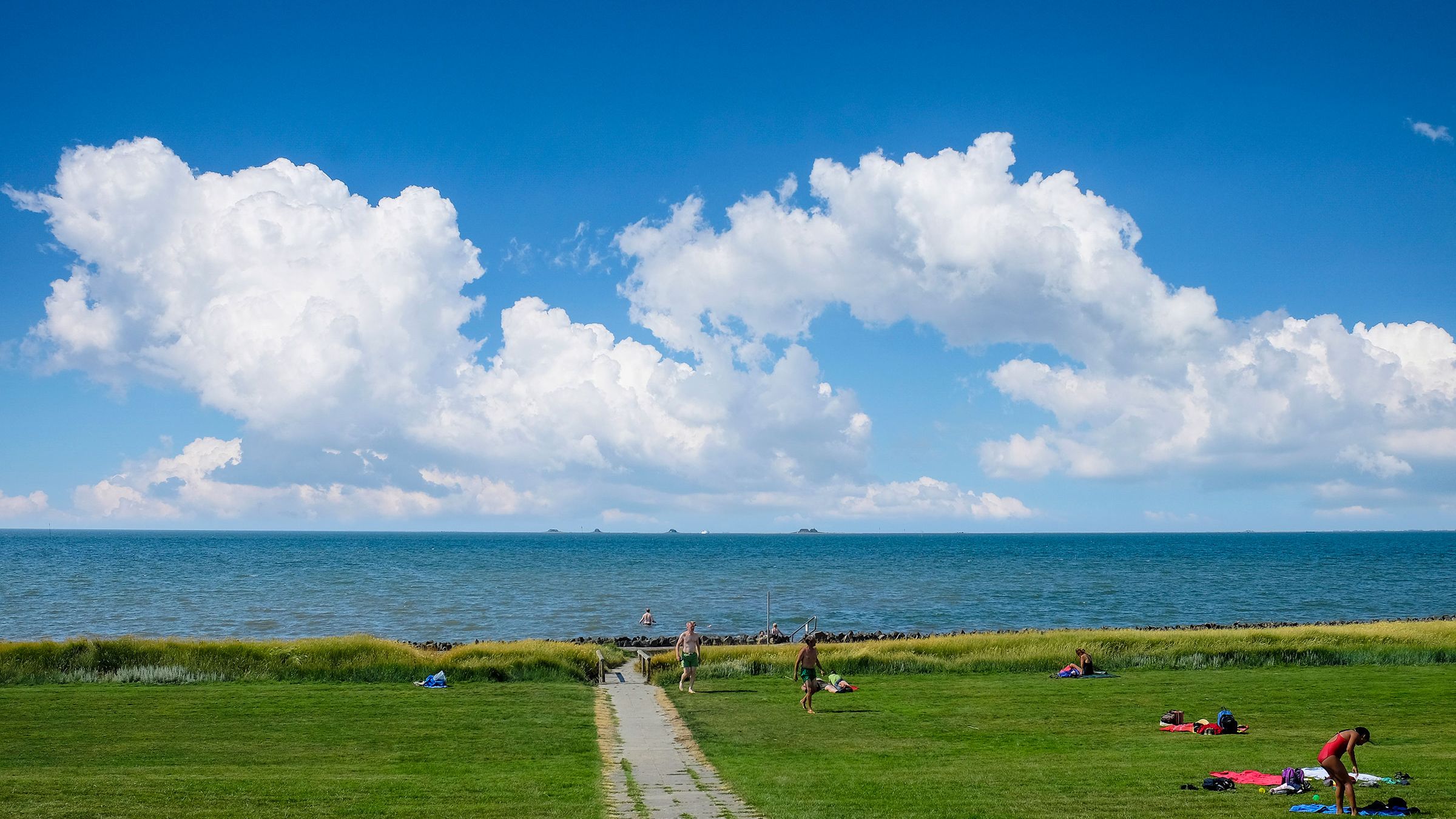 Blick auf den Badestrand Oben bei Hochwasser im Sommer mit Blick auf die Hallig Nordstrandischmoor.