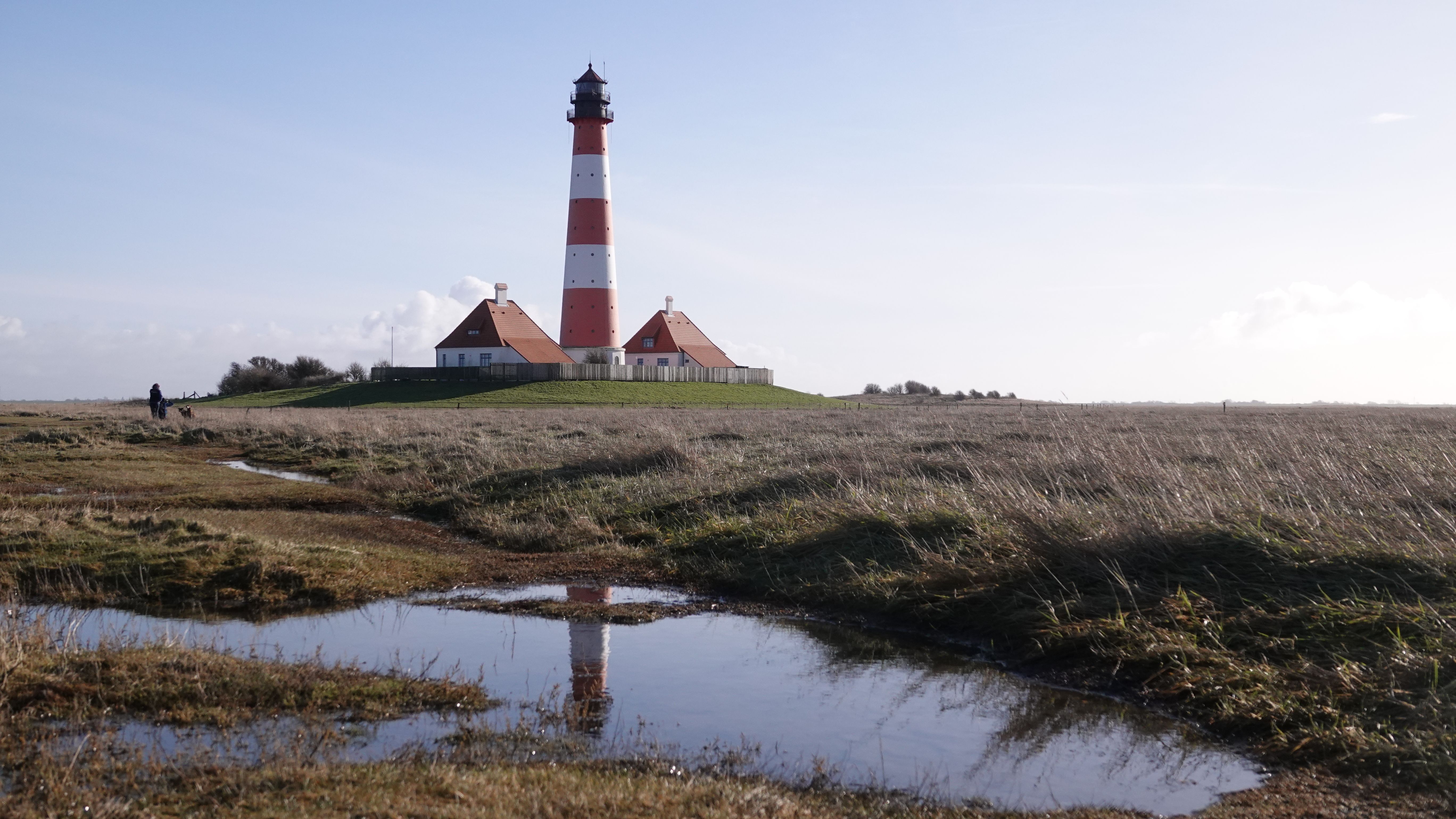 Leuchtturm Westerhever, der sich in einer Wasserpfütze spiegelt. 